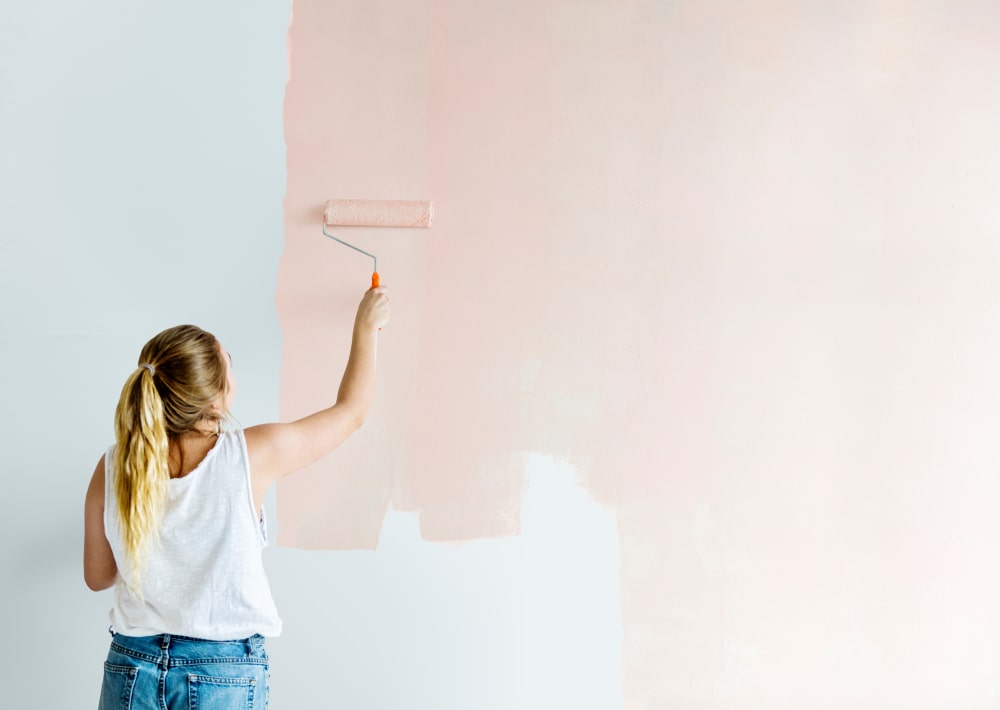 woman painting her walls pink as a budget home upgrade to add value